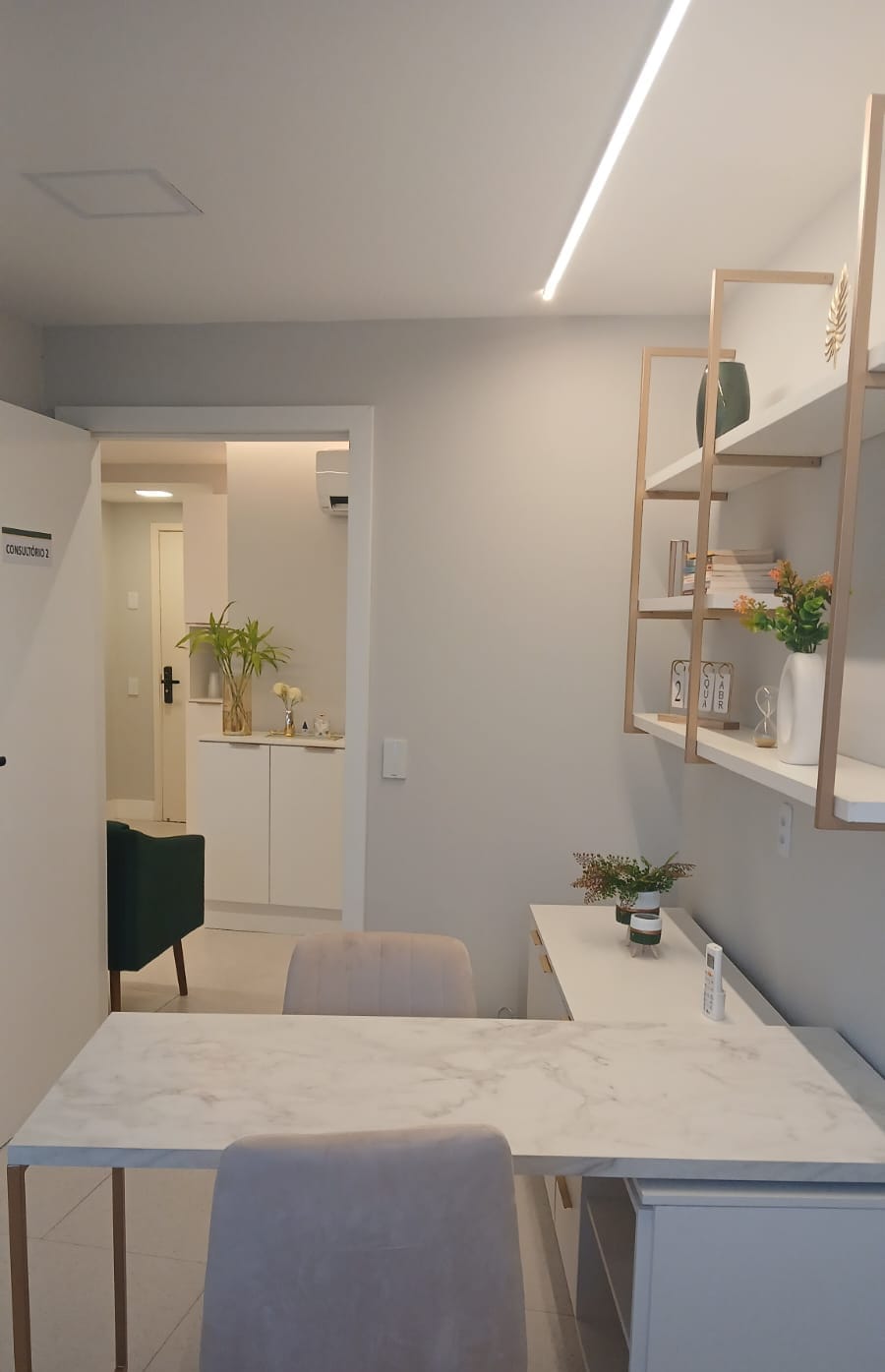 Segundo consultório de terapia e psicologia da LIV Saúde Integrativa com mesa de mármore e prateleiras